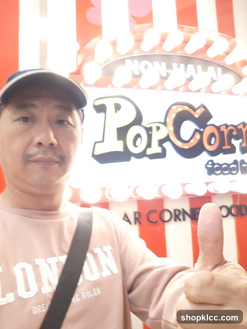 Man giving a thumbs up in front of a popcorn sign