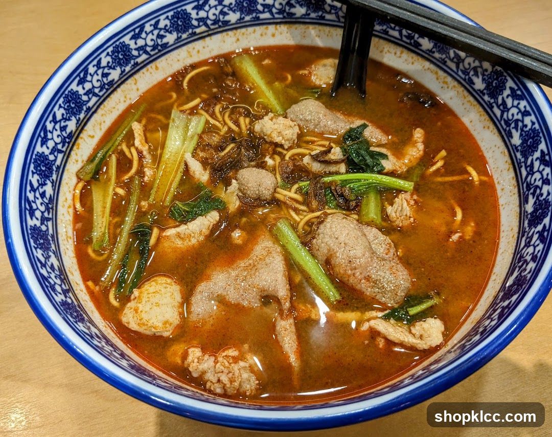 Bowl of Spicy Noodle Soup with Meatballs and Greens