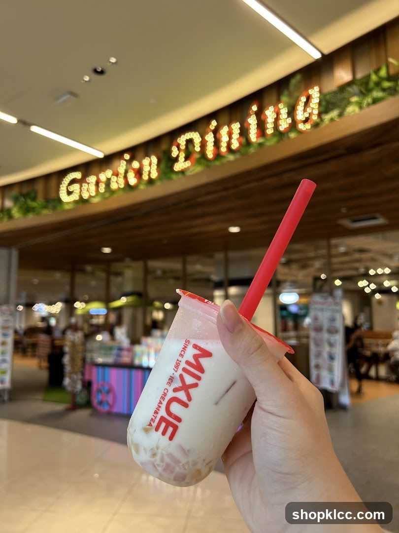 Hand holding a bubble tea drink with a store sign in the background