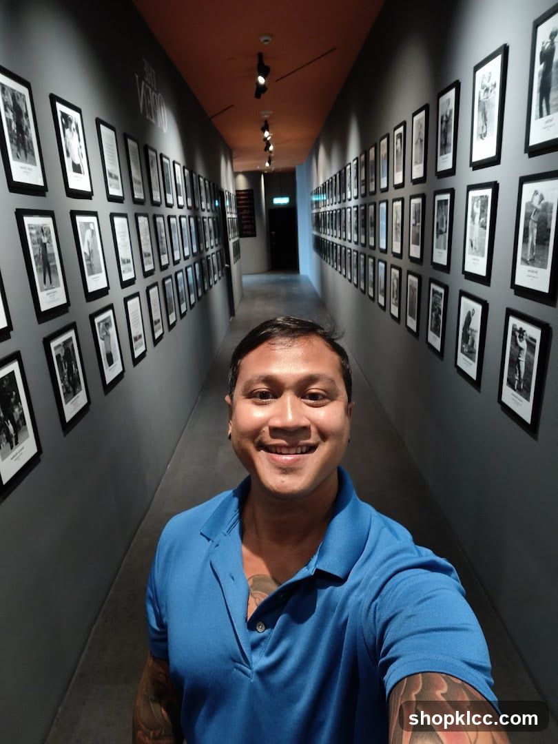 Man in Blue Polo Shirt in Hallway with Framed Photos