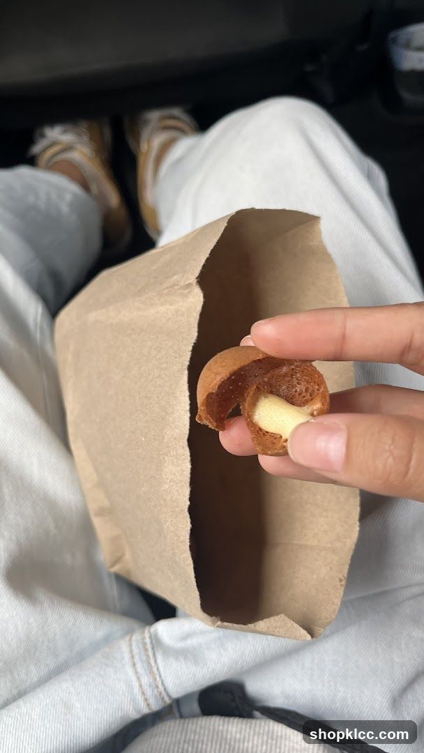 Person holding a pastry from a paper bag