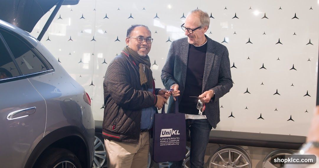 Two men exchanging items near a car