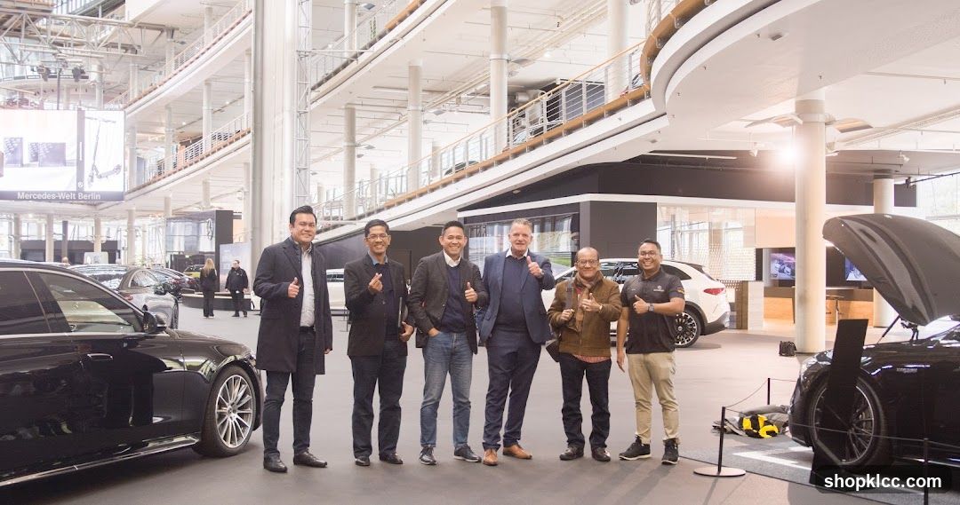 Group of men posing with cars in showroom