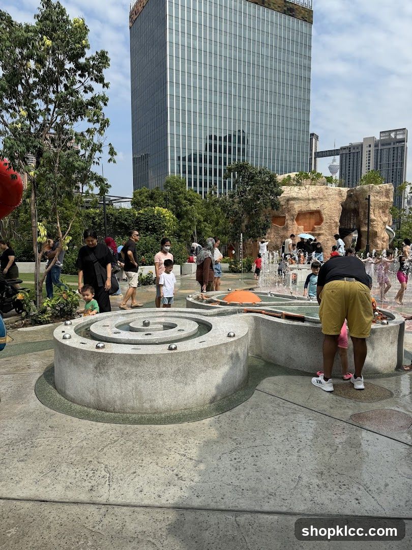 People enjoying a water play area with a skyscraper in the background