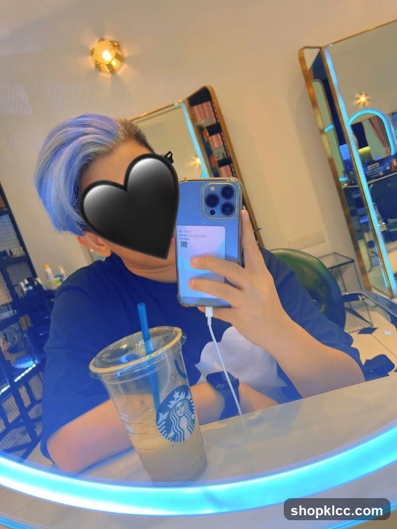 Person with blue-tinted hair taking a selfie in a salon