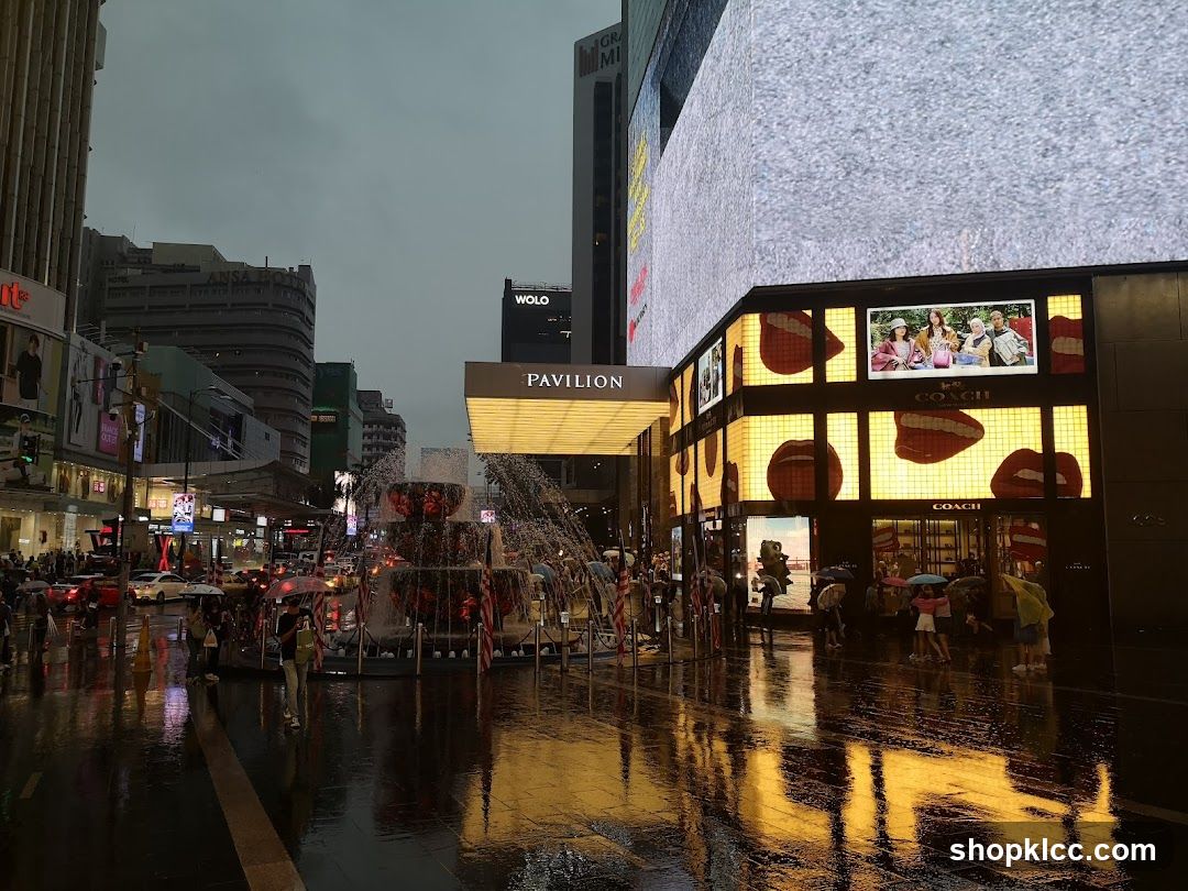 Rainy street with fountain and illuminated buildings