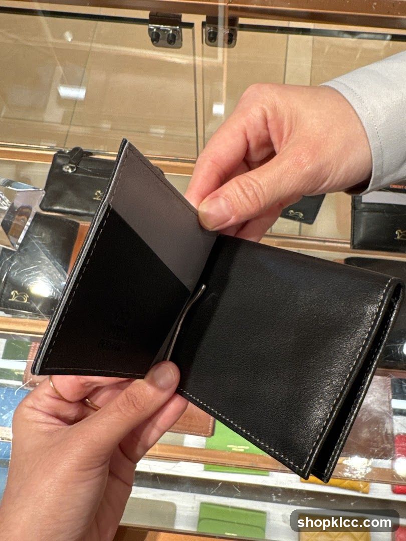 Hands holding a black leather wallet with a money clip