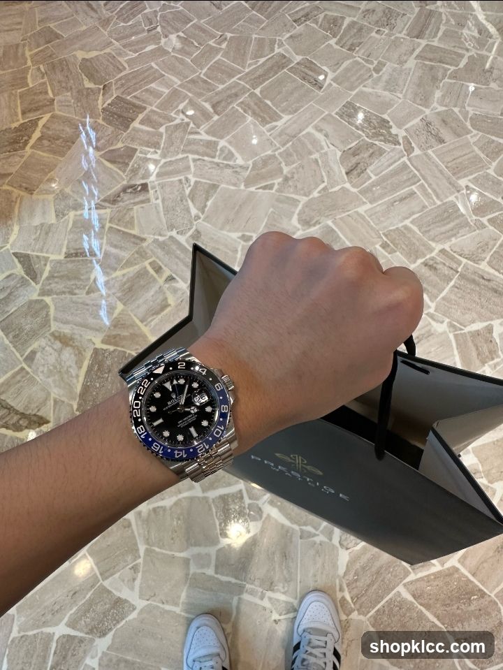 Person holding a shopping bag with a watch on their wrist