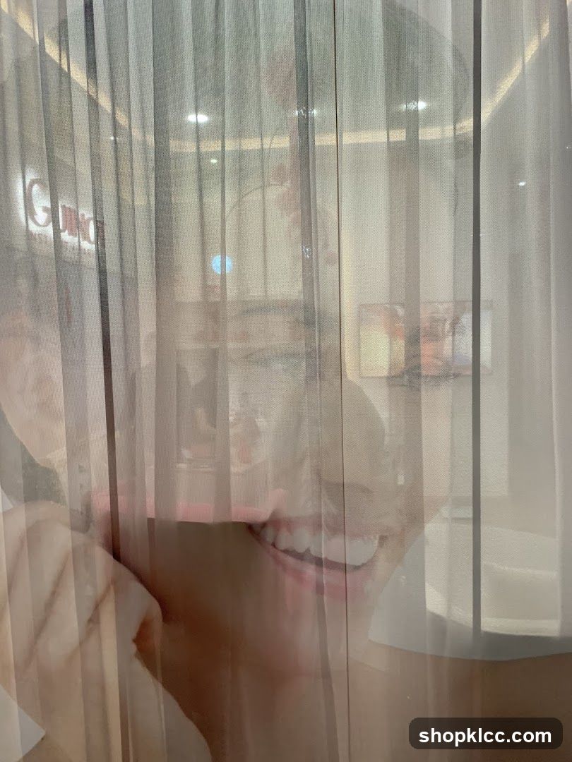 Reflection of a smiling person behind sheer curtains