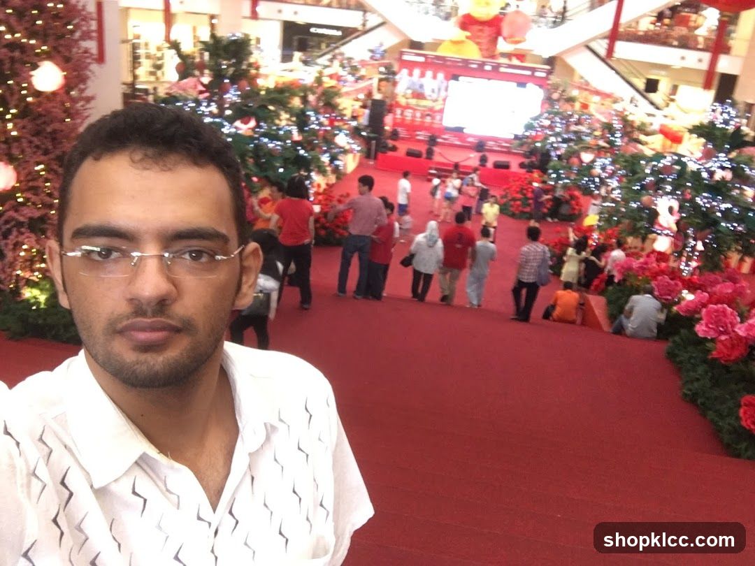 Man taking a selfie in a mall decorated for Christmas
