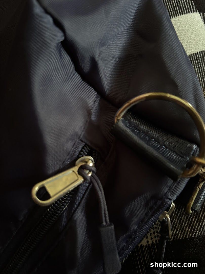 Close-up of a dark blue bag with a zipper and a gold ring.