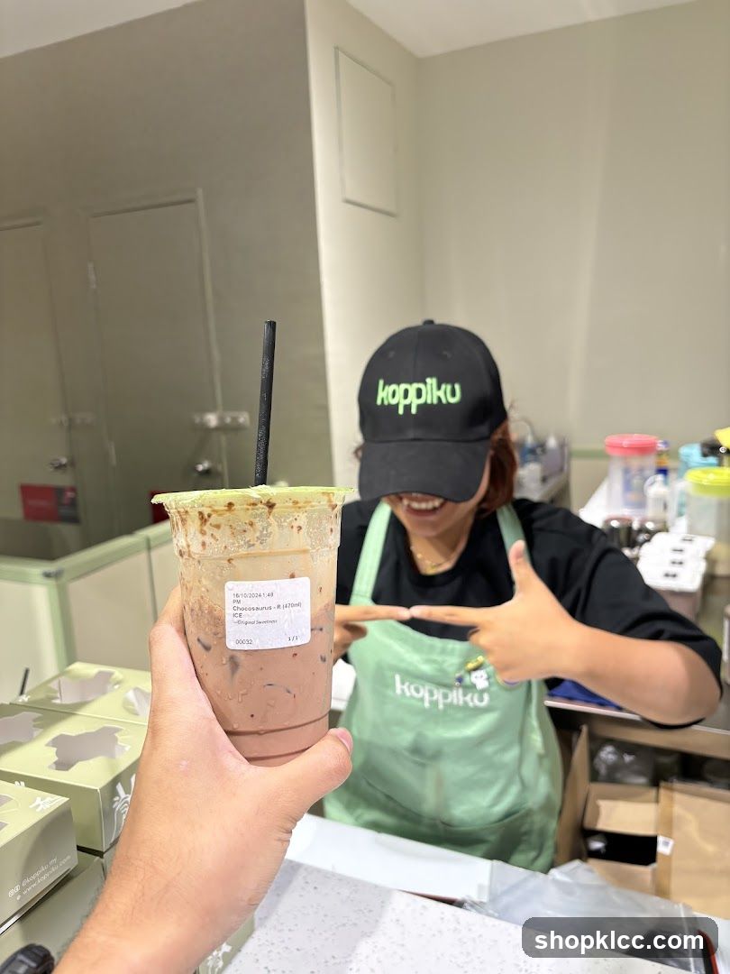 Customer holding a drink with a staff member in the background