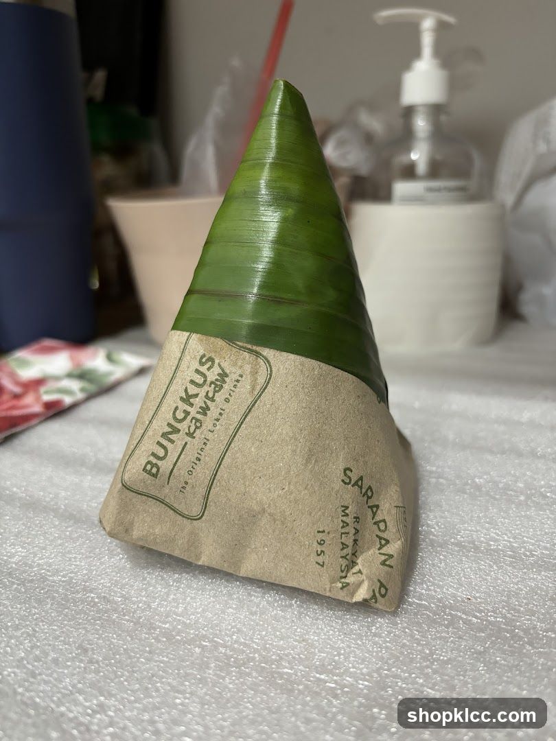Food item wrapped in banana leaf and paper