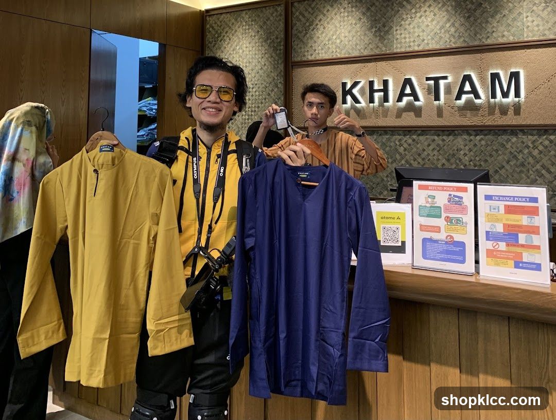 Two men holding up clothing items in front of a store counter