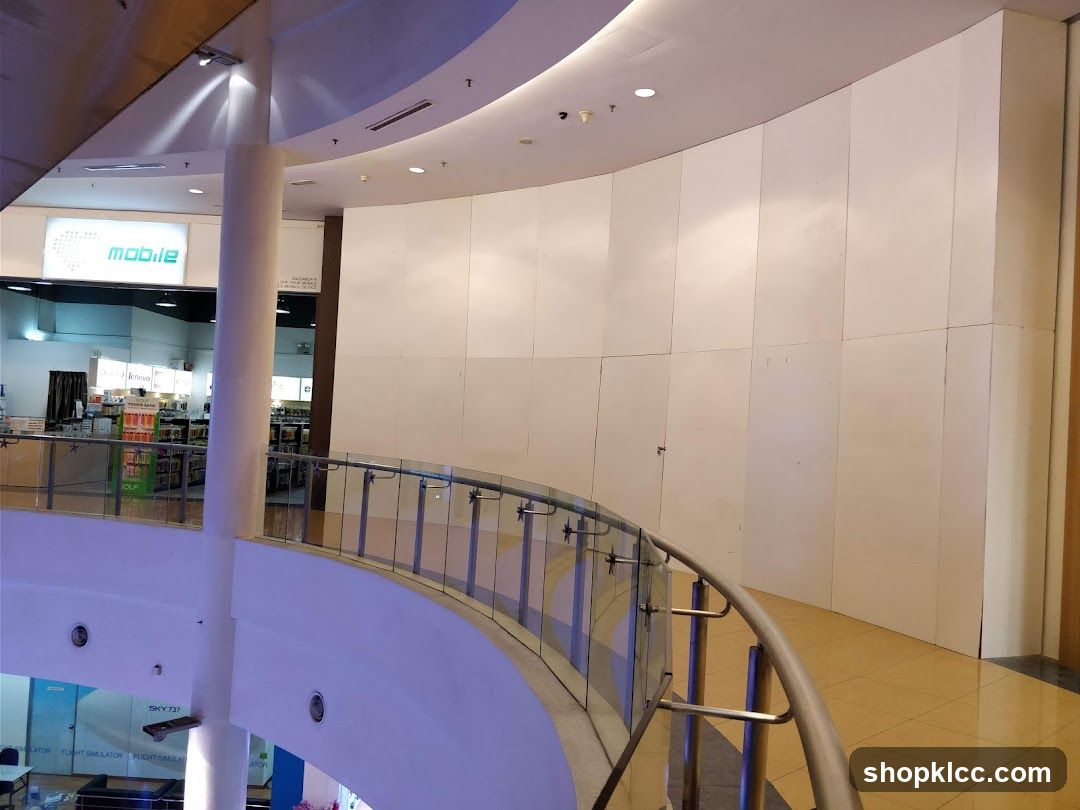 Interior of a shopping mall with a curved railing and a store sign