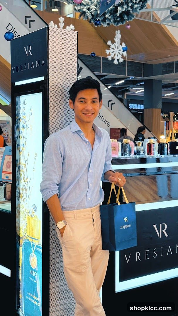 Man Posing with Shopping Bag and Perfume Display