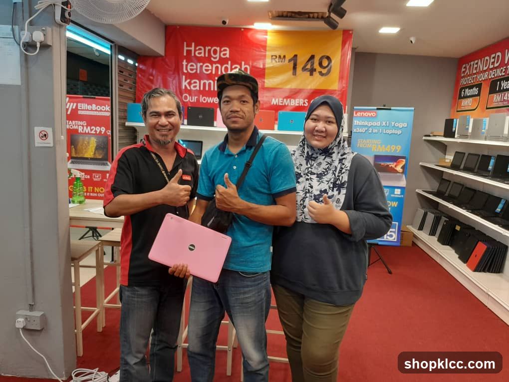 Three people posing with a laptop in a store