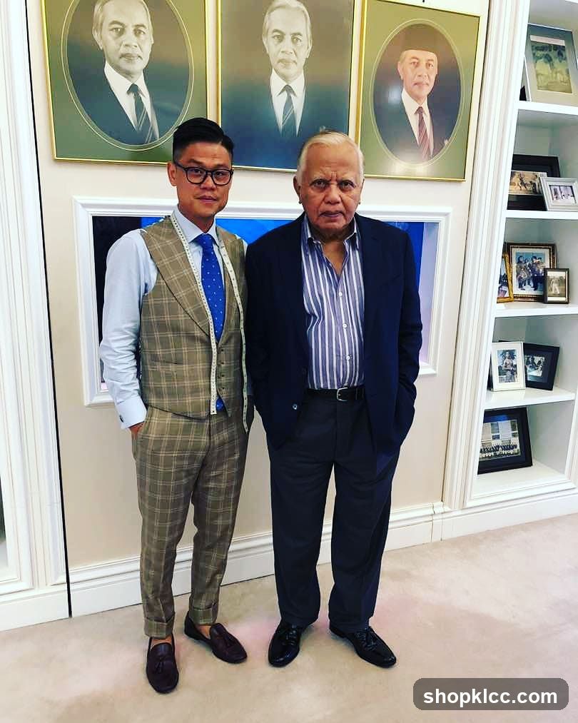 Two men posing indoors with framed portraits in background