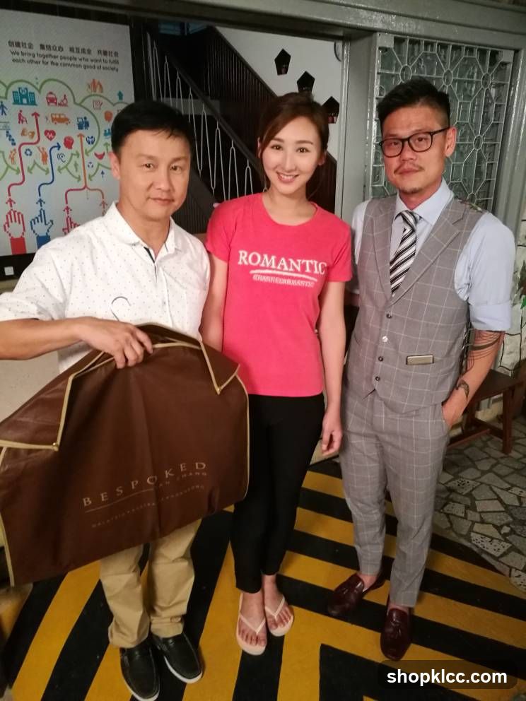 Three people posing indoors with a garment bag