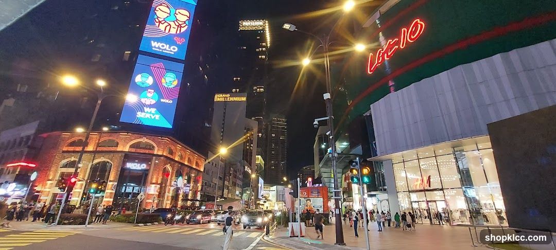 Nighttime street view of a busy urban area with illuminated buildings and traffic.