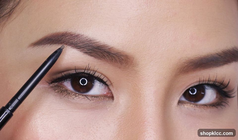 Close-up of a person's eye and eyebrow being filled in with a pencil.