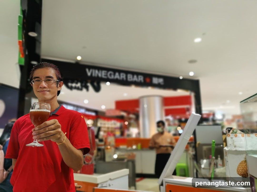Man holding a drink in front of a Vinegar Bar