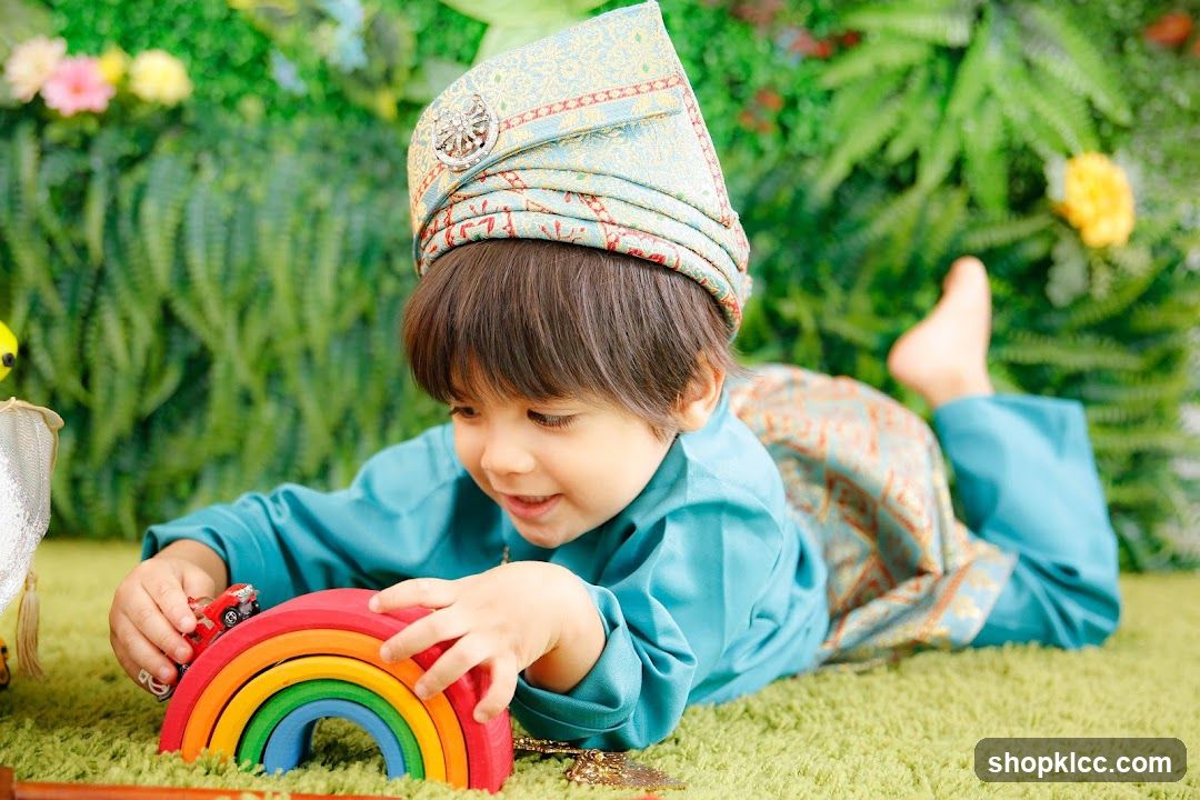 A young boy in traditional attire plays with a rainbow toy.