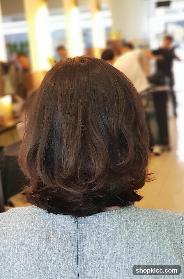 Back of a person with short brown hair in a salon or cafe setting
