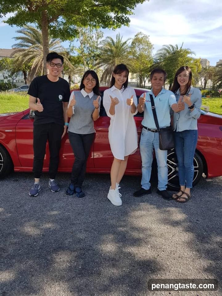 Group posing with a red car