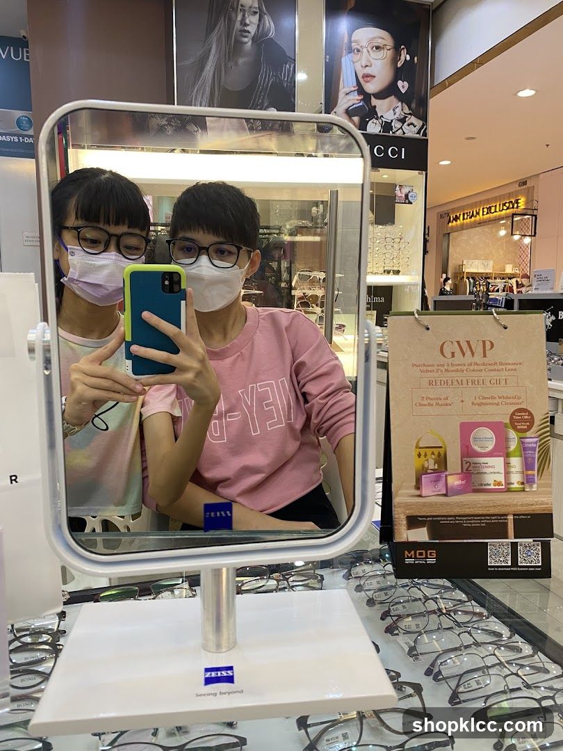 Two people taking a mirror selfie in an optical shop