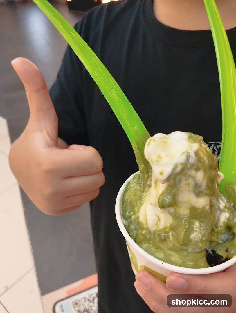 Person giving a thumbs up with a cup of soft serve ice cream