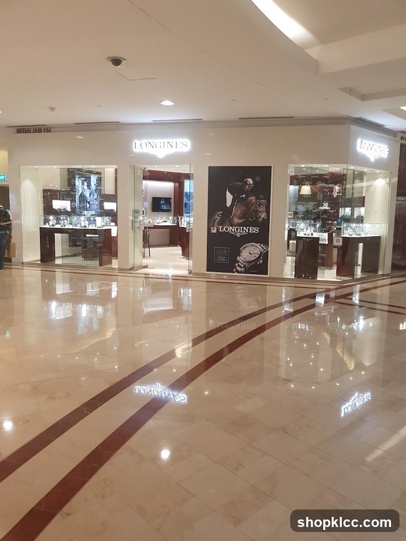 The exterior of a Longines watch store in a mall. The store has large glass windows displaying watches and a prominent illuminated 'LONGINES' sign above the entrance. A large promotional poster featuring a horse rider and a watch is displayed on the right side of the entrance. The floor is polished marble with red and white stripes.