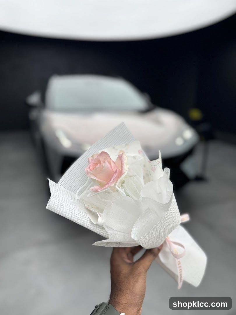 Hand holding a bouquet of flowers in front of a car