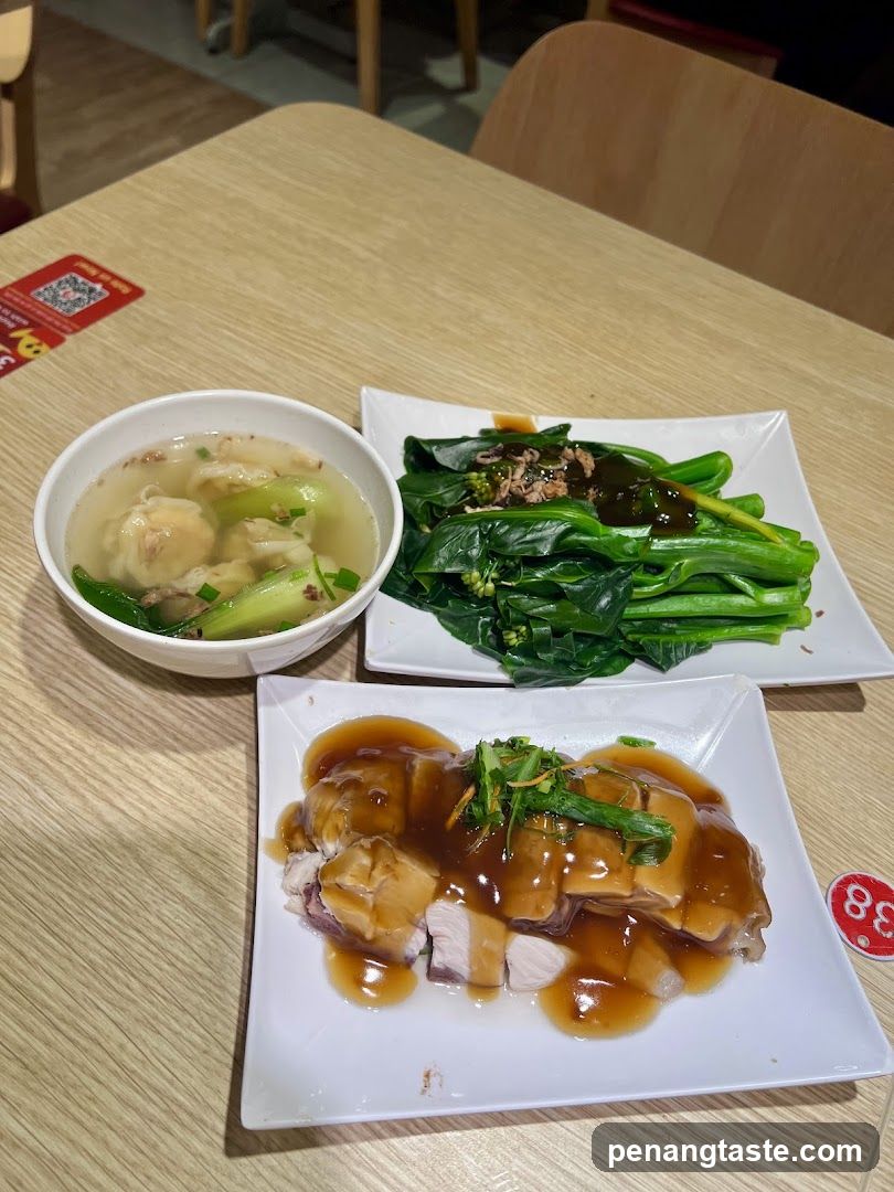 Slices of roasted meat with gravy, a bowl of wonton soup, and a plate of steamed greens