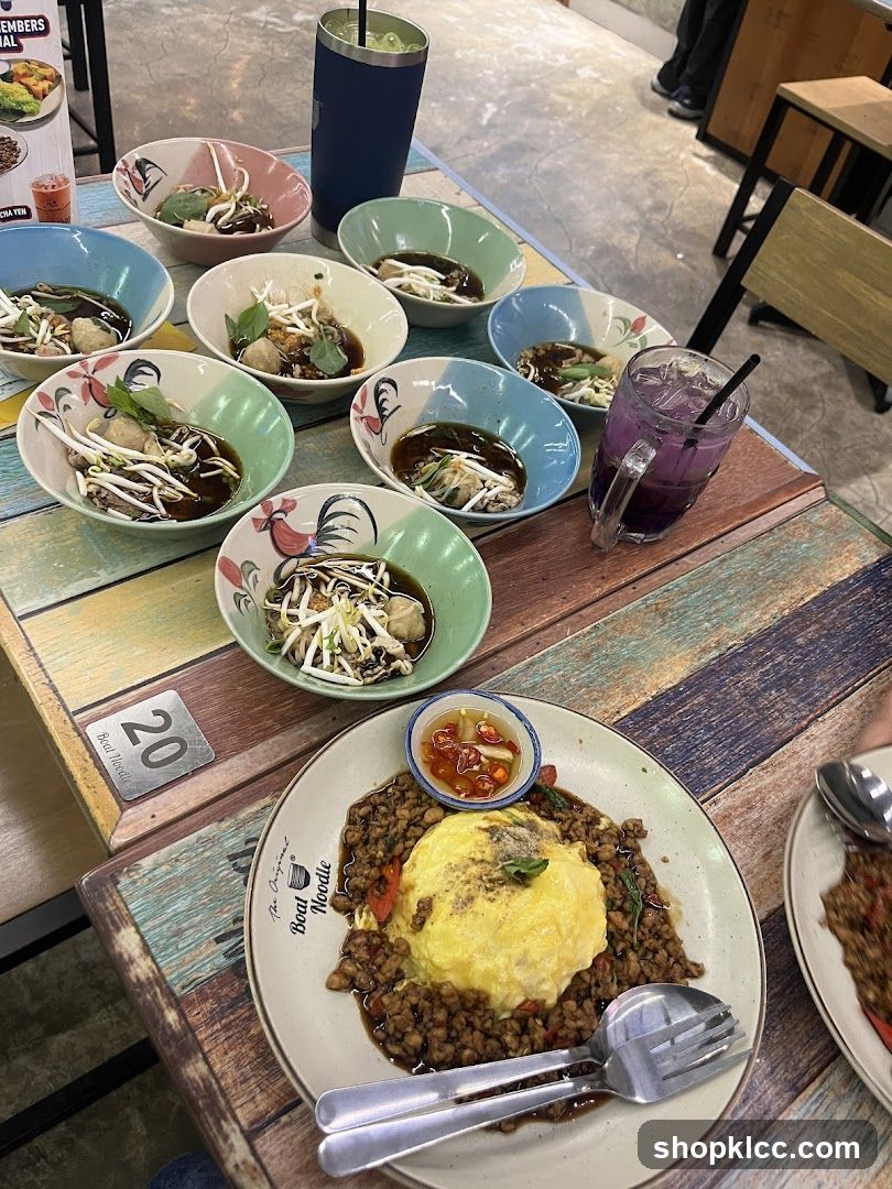 Table with multiple bowls of noodles and a plate of rice with omelet
