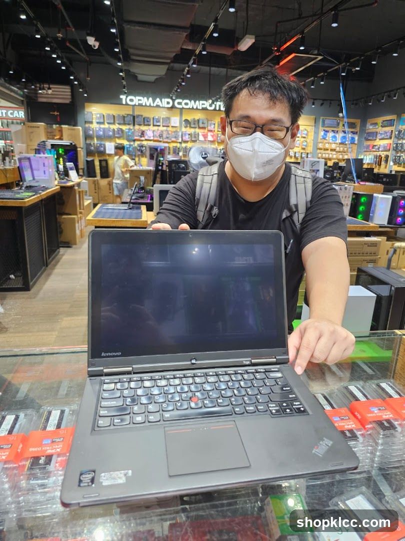 Man holding a laptop in a computer store