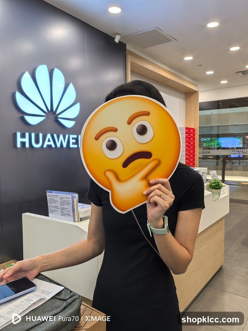 Person holding an emoji mask in front of Huawei logo