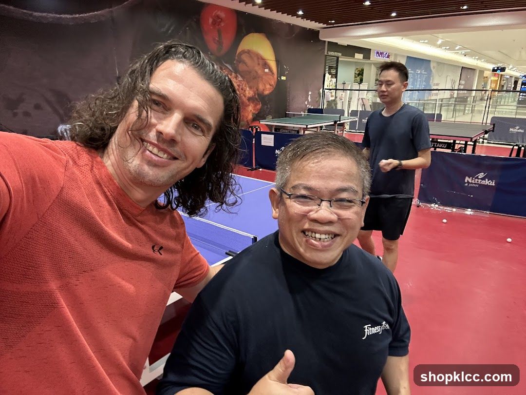 Two men posing for a selfie at a table tennis facility