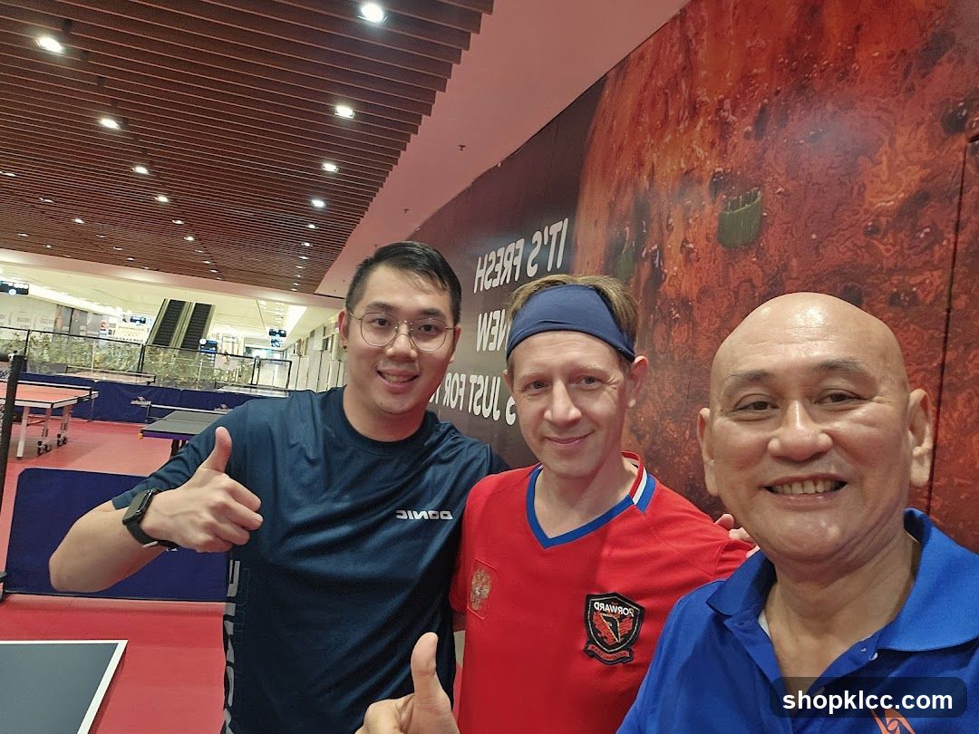 Three men posing for a selfie in a table tennis facility