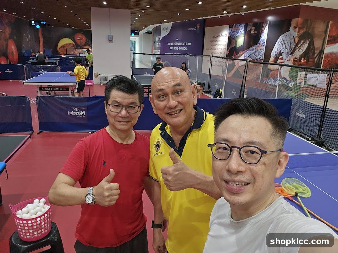 Three men posing for a selfie at a table tennis facility