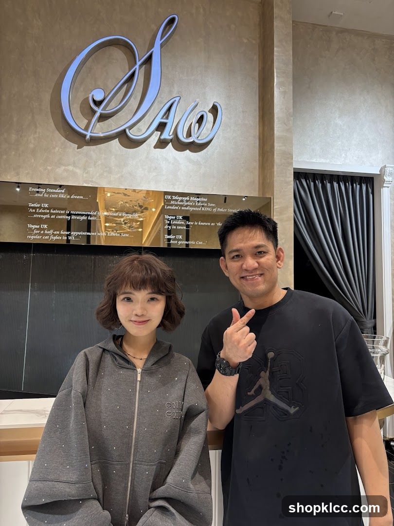 Two people posing in front of a salon sign