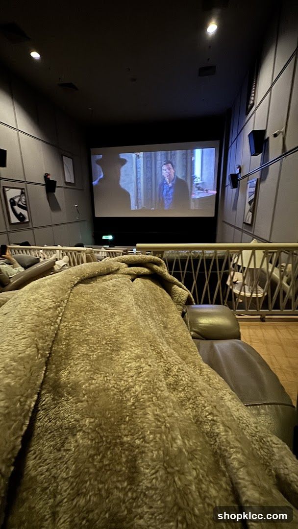 Movie theater interior with reclining seats and a movie playing on screen.