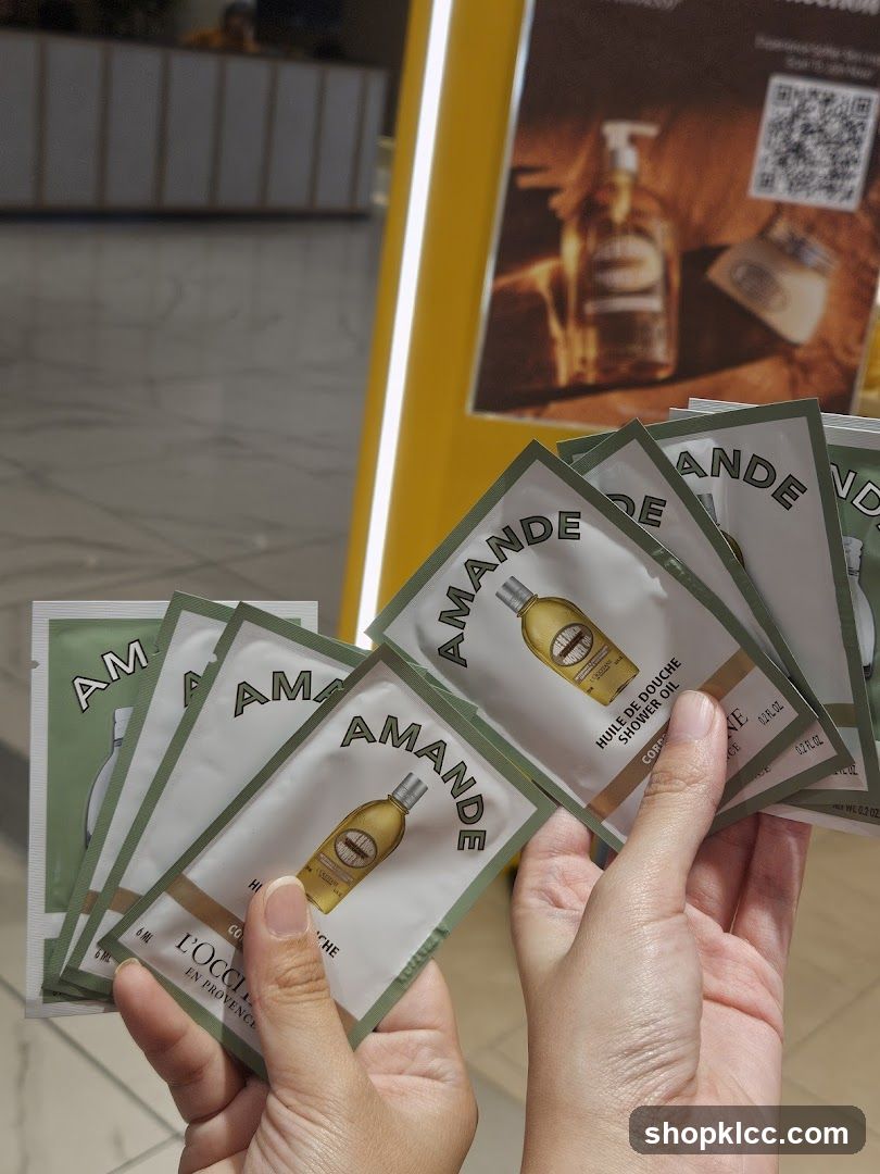 Hand holding sample packets of L'Occitane Almond Shower Oil