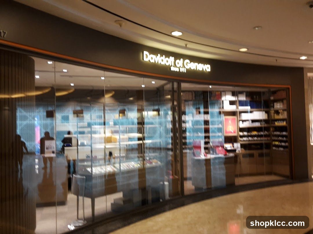 The exterior of a Davidoff of Geneva store. The store has a large glass facade with the store name illuminated above the entrance. Inside, shelves are stocked with various products, and display cases are visible.