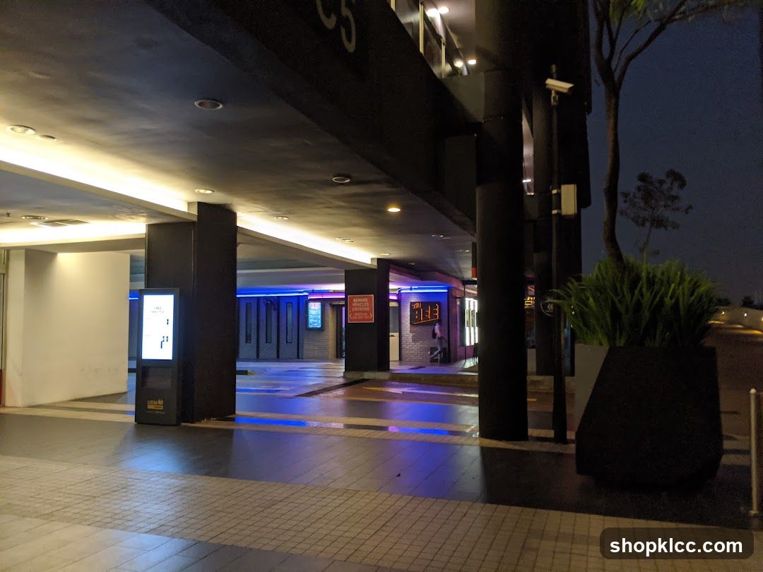 Nighttime view of a covered walkway with illuminated signs and planters