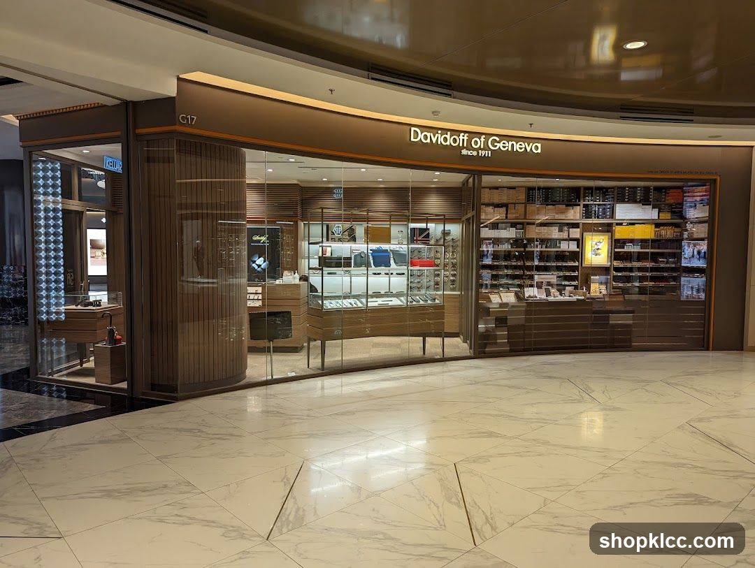 The exterior of a Davidoff of Geneva store, featuring a large glass facade displaying various products. The store's name is prominently displayed above the entrance. Inside, shelves are stocked with boxes of cigars and other merchandise. Display cases showcase watches and accessories. The store is located in a mall with marble flooring.