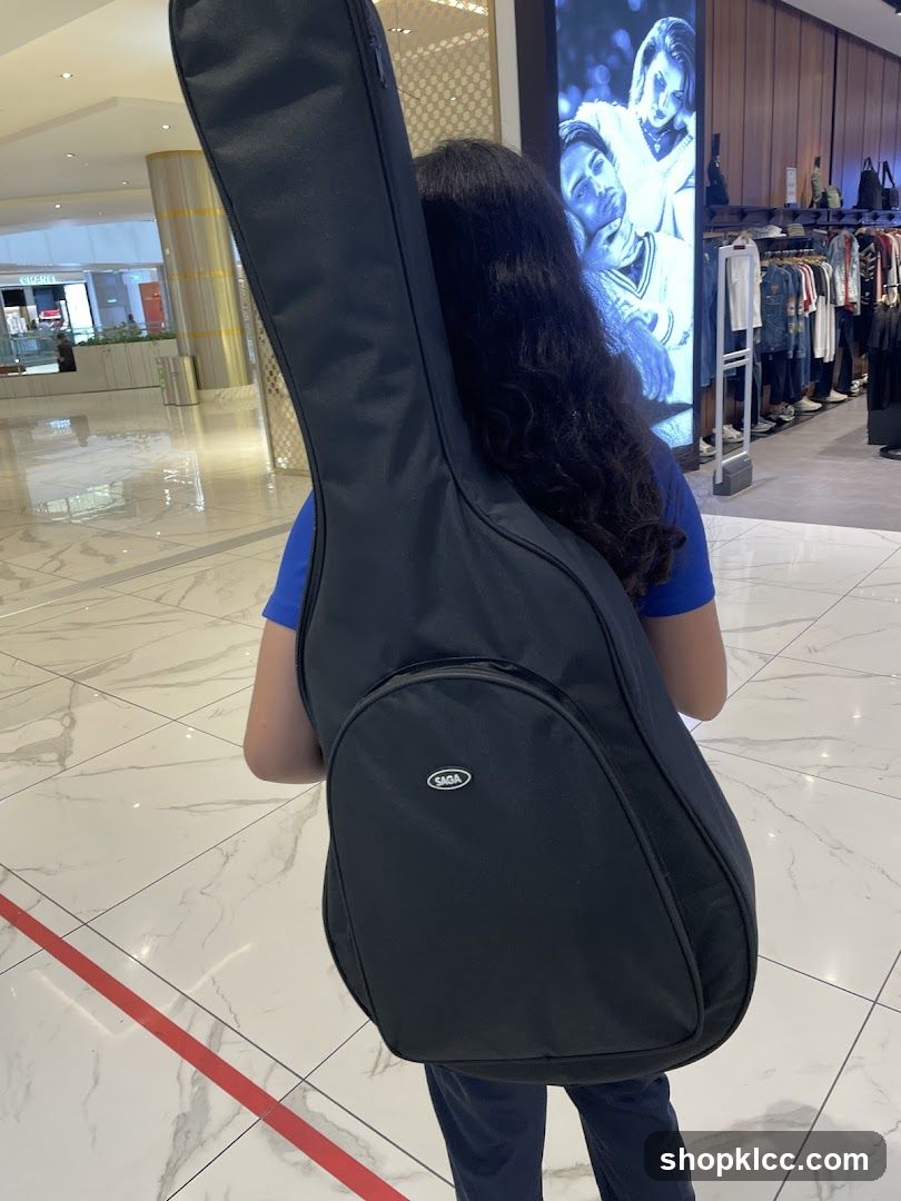 Person carrying a guitar case in a mall