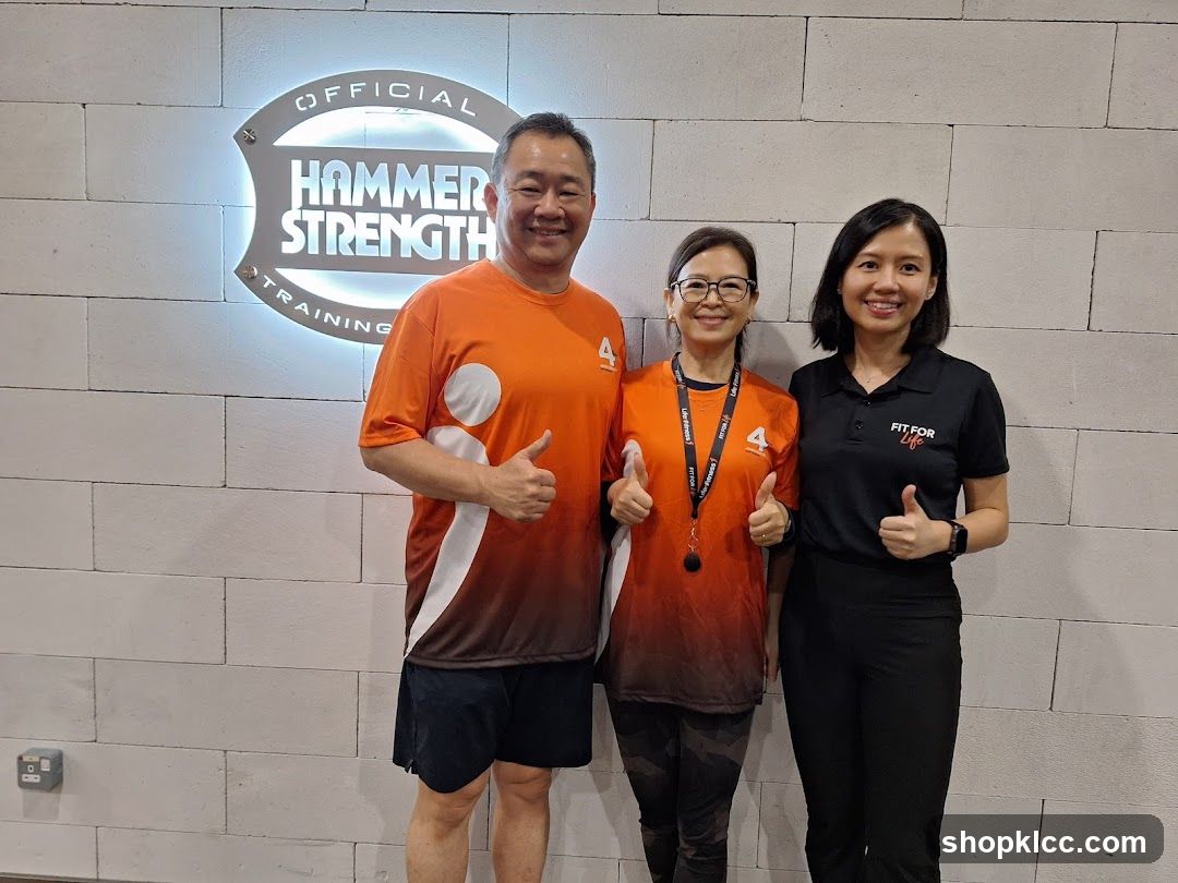 Three people posing in front of a Hammer Strength Training sign