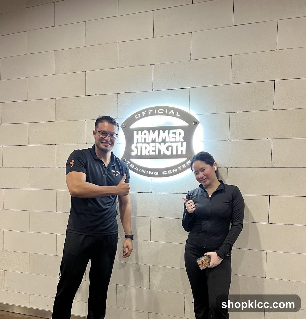 Two people posing in front of a Hammer Strength sign