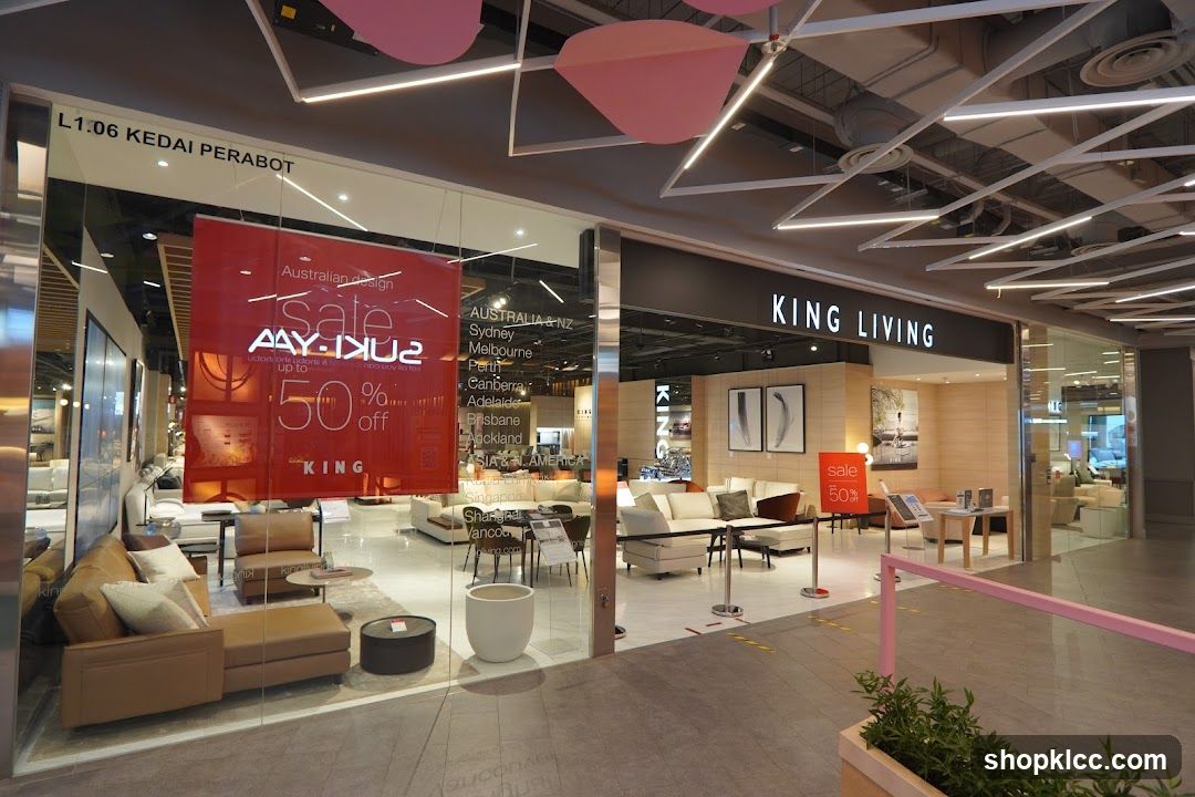 The exterior of a King Living furniture store. A large red banner on the window advertises a sale of up to 50% off. The store interior displays various sofas and furniture arrangements. The store name "KING LIVING" is visible above the entrance.
